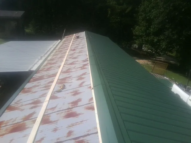 Old rusted panels beside newly installed green metal roofing — Wind Damage Roof Repair by Roofing Brothers in Glendale
