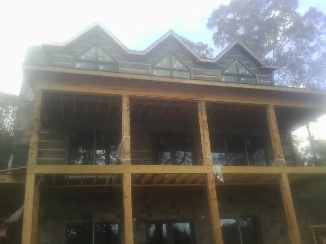 Dormers and porch framing on a large log home under construction — Roof Coating work by our crew in Glendale